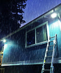 Faretto solare LED impermeabile IP66 che illumina edificio durante forte pioggia notturna - Resistenza agli agenti atmosferici e illuminazione potente garantita in qualsiasi condizione meteo