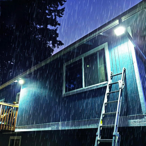 Faretto solare LED impermeabile IP66 che illumina edificio durante forte pioggia notturna - Resistenza agli agenti atmosferici e illuminazione potente garantita in qualsiasi condizione meteo