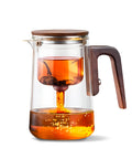 Teiera vetro con infusore in azione: tè caldo in infusione, sistema filtro separazione visibile, design elegante trasparente